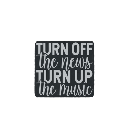 Slate coaster with the quote “Turn off the news, turn up the music” engraved.