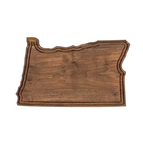 Walnut cutting board shaped like the state of Oregon, featuring a carved juice groove around the perimeter to catch drips.