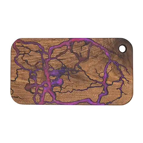 Rounded-rectangle walnut charcuterie board with a purple fractal burn pattern inlaid with food-safe epoxy.